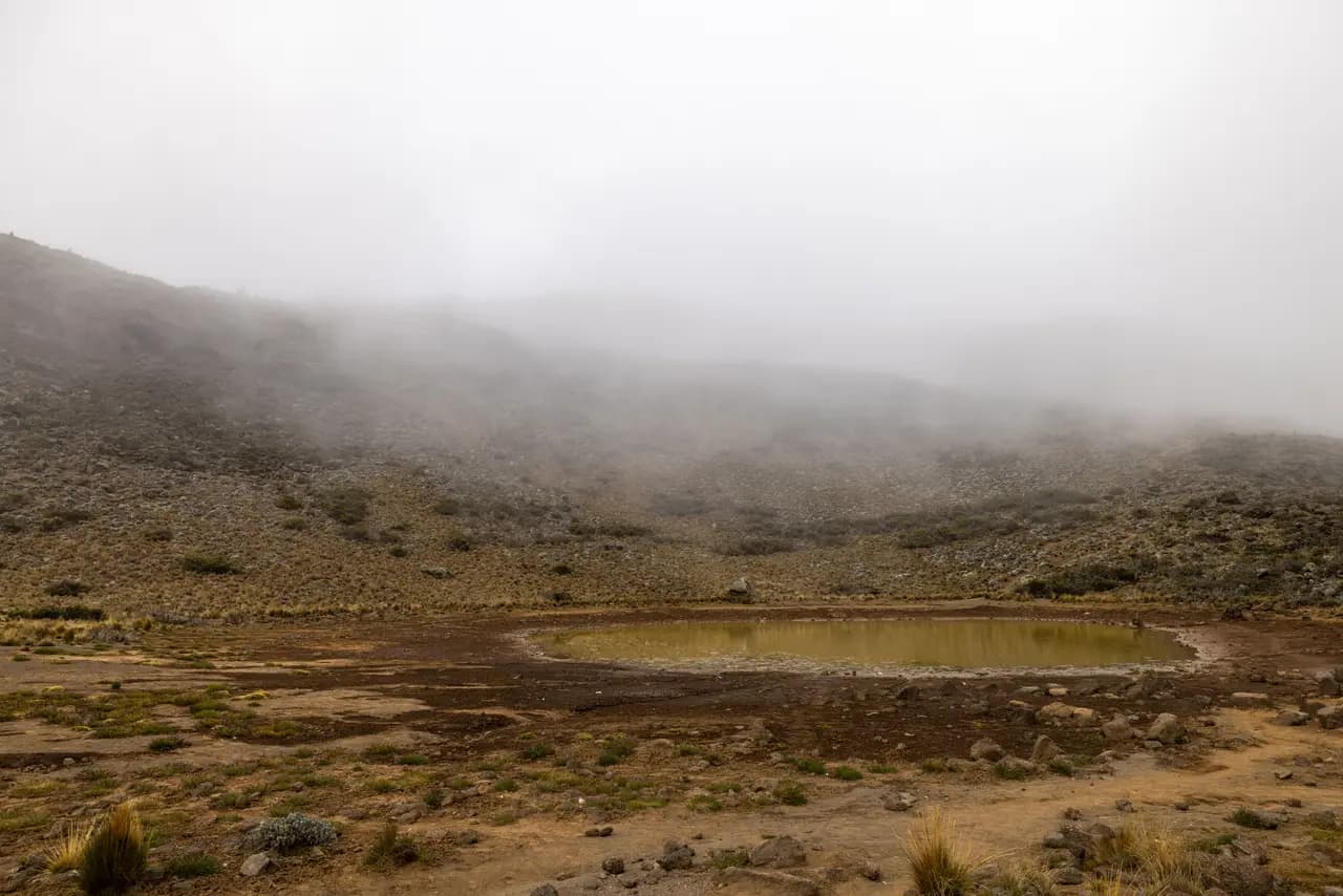 Small mountain lake in a rocky landscape covered with thick fog and low clouds in the highlands