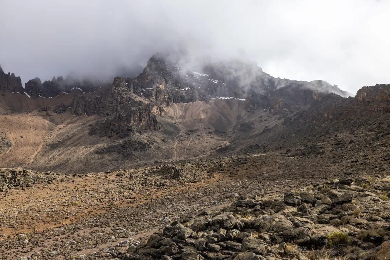 Rugged mountain landscape with rocky terrain and misty clouds covering the high peak summit